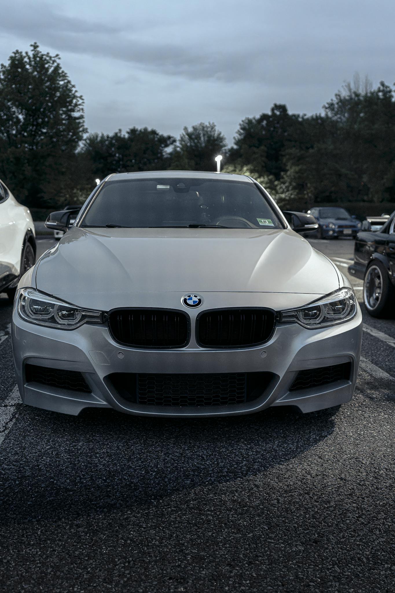 Front view of a silver luxury sedan parked outdoors in a parking lot during daytime.