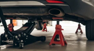 Car supported by jack stands after being lifted with hydraulic floor jack